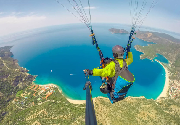 Paragliding in the sky. Paraglider tandem flying over the sea with blue water and mountains in bright sunny day. Aerial view of paraglider and Blue Lagoon in Oludeniz, Turkey. Extreme sport. Landscape - Photo, Image