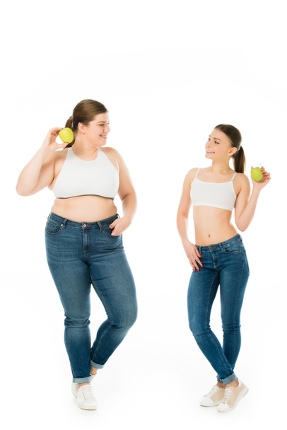 happy slim and overweight women with green apples looking at each other isolated on white - Foto, Imagen