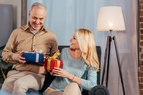 attractive wife and smiling near husband holding gift boxes in hands - Photo, image