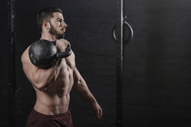 Portrét sportovec drží kettlebell cvičení crossfit v tělocvičně. Kopírovat prostoru. Pohledný muž dělá funkční trénink. Cvičení cvičení - Fotografie, Obrázek