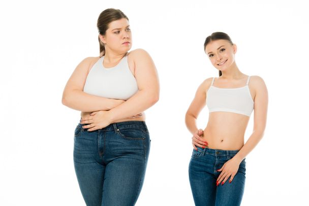 sad overweight woman covering body with hands and looking at slim happy woman isolated on white - Photo, Image