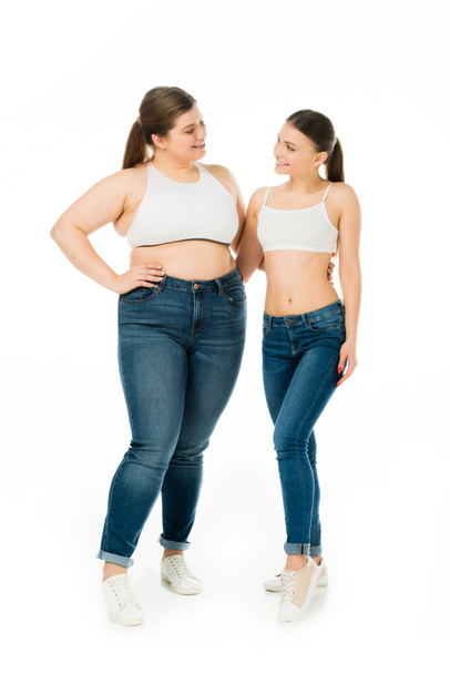 happy slim and overweight women hugging and looking at each other isolated on white, body positivity concept - Foto, imagen