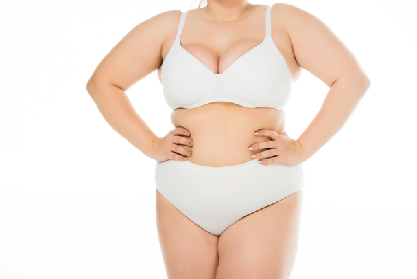 Ausgeschnittene Ansicht einer übergewichtigen Frau in Unterwäsche mit den Händen auf den Hüften, isoliert auf weiß, Body-Positivity-Konzept  - Foto, Bild