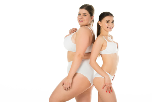 jovens mulheres magras e com excesso de peso em roupa interior posando juntos isolado no branco
 - Foto, Imagem