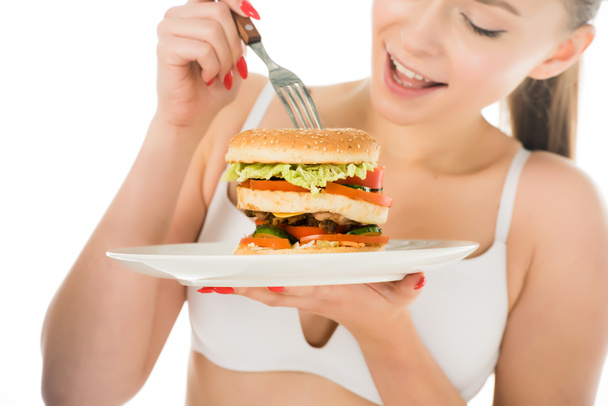 lähikuva kaunis nainen alusvaatteet syöminen maukas hampurilainen haarukalla lautaselta eristetty valkoinen
 - Valokuva, kuva