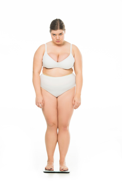 sad young overweight woman standing on scales isolated on white, lose weight concept - Photo, Image