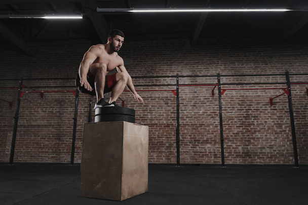 Young athlete doing box jump at crossfit gym. Workout exercises. Copy space - Фото, зображення