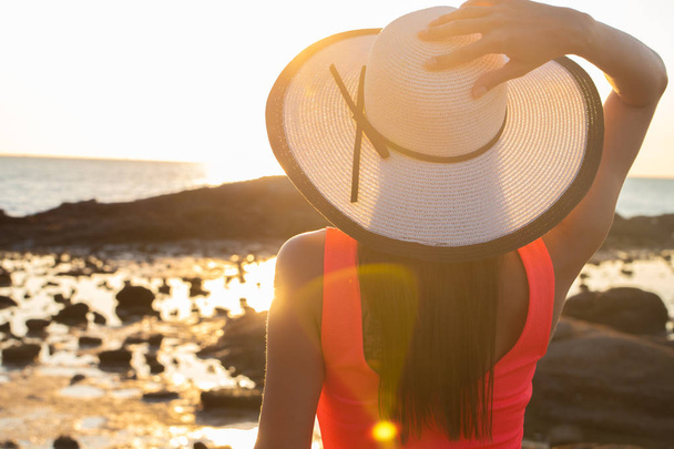κορίτσι σε ένα καπέλο βόλτες κατά μήκος της παραλίας στο ηλιοβασίλεμα - Φωτογραφία, εικόνα