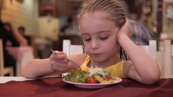 little girl eat green salad with appetite in the restaurant. Good health concept - Footage, Video