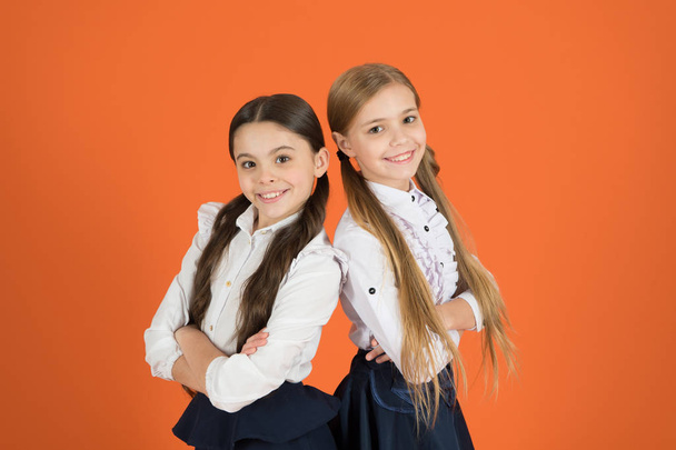 In traditional black and white. Little girls wearing school uniform. School children with a fashion forward look. Cute schoolgirls. Small girls in pigtails dressed for school. Back to school fashion - Valokuva, kuva