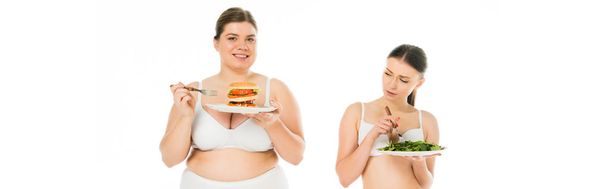 nadváhou usmívající se žena v prádle drží burger na desku zároveň tenký šťastná žena jíst zelené špenátovými listy izolované na bílém - Fotografie, Obrázek