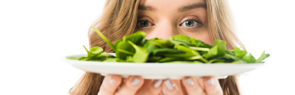 selective focus of young woman holding plate with green spinach leaves isolated on white - Photo, Image