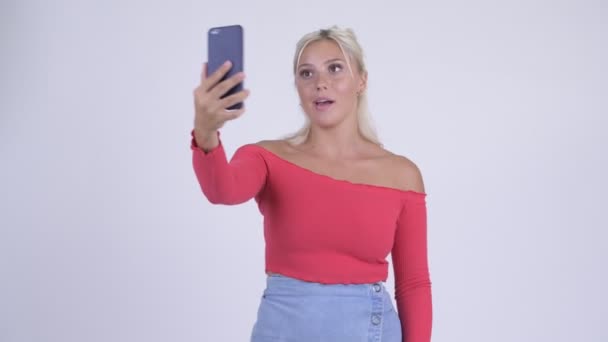 Happy young beautiful blonde woman video calling with phone - Felvétel, videó