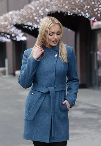 Beautiful young stylish blonde woman wearing coat walking through the city streets. Trendy casual outfit. Street fashion - Photo, Image
