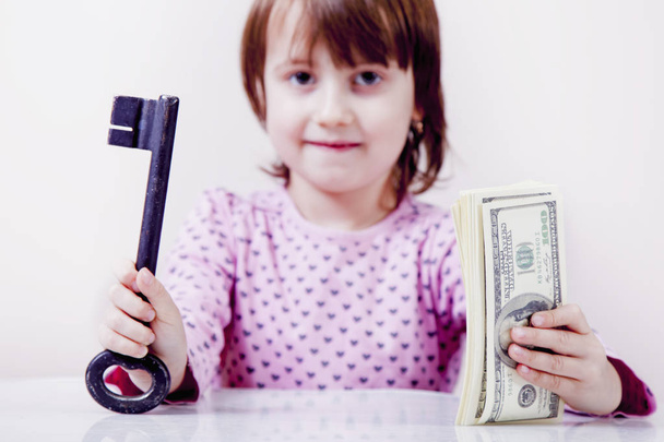 Klíč ke konceptu bohatství. Roztomilé holčička drží klíč jako sym - Fotografie, Obrázek