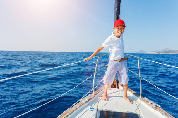 Little boy on board of sailing yacht on summer cruise. Travel adventure, yachting with child on family vacation. - Photo, image