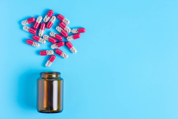 Różowe pigułki, tabletki w brązowy butelka na niebieski backgrou - Zdjęcie, obraz