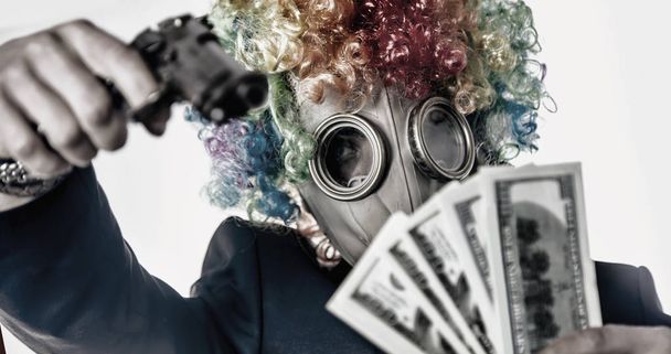 Mannelijke gangster met masker clown met pistool neemt het geld. Crimin - Foto, afbeelding