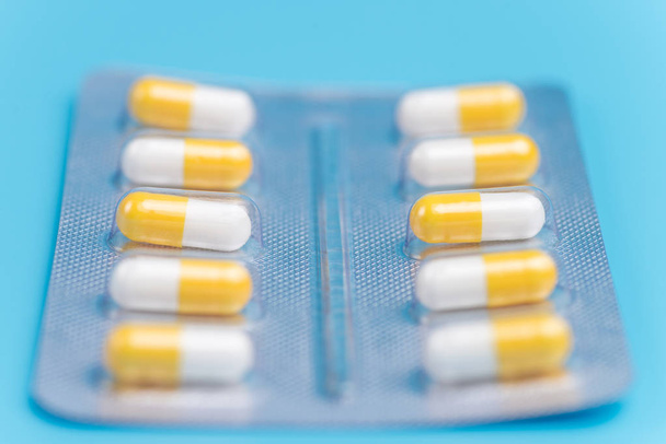 Medicina píldoras blancas y amarillas empaquetadas en ampollas en respaldo azul
 - Foto, imagen
