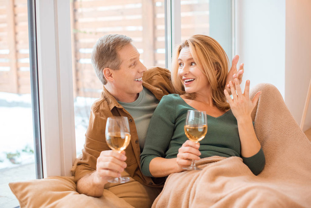 happy couple holding glasses of white wine and looking at each other - Photo, Image