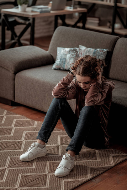 Teenage girl sitting on floor while having deep depression - Фото, изображение
