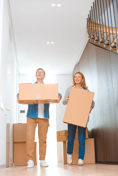 happy couple holding cardboard boxes at new home - Photo, Image