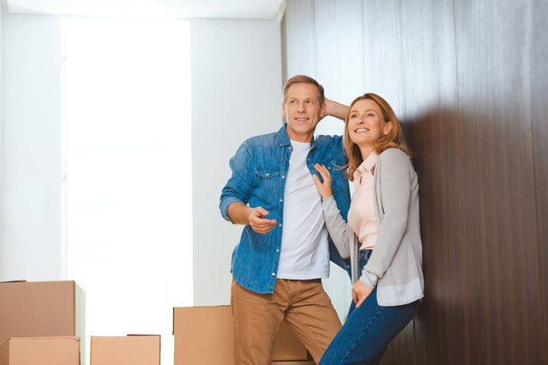 happy couple standing by wall near cardboard boxes - Photo, Image