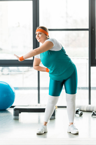 cheerful overweight woman training in sportswear in gym - Foto, afbeelding