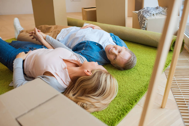 selective focus of happy couple lying on floor on green carpet - Photo, image