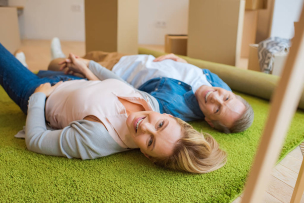foyer sélectif de couple heureux couché sur le tapis vert et regardant la caméra
 - Photo, image