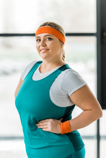 cheerful overweight woman smiling while posing in gym - Фото, зображення