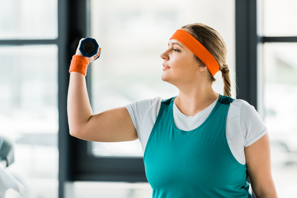 Übergewichtige Frau trainiert in Sportbekleidung mit Hantel - Foto, Bild