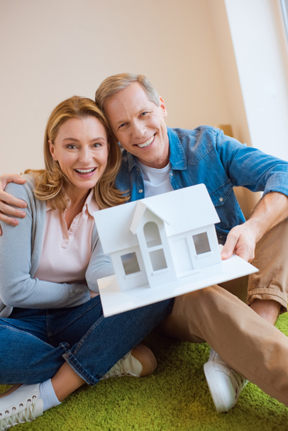 happy couple demonstrating house model while looking at camera - Foto, Bild