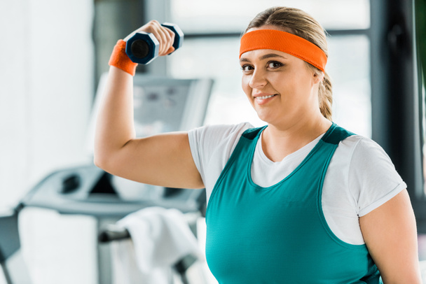 Gelukkig overgewicht vrouw workouting in sportkleding met halter - Foto, afbeelding