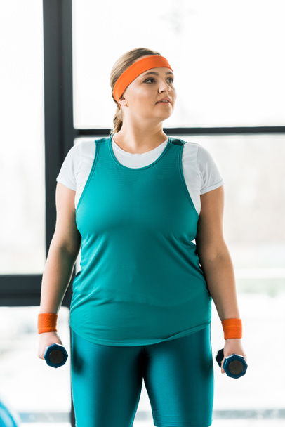pensive overweight woman workouting in sportswear with dumbbells - 写真・画像