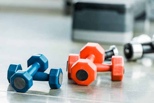 selective focus of metallic multicolored fitness dumbbells in gym - Foto, immagini