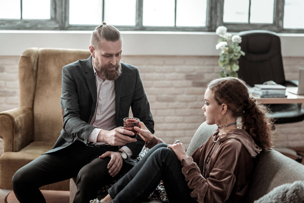Bearded counselor bringing glass of water to nervous teenager - Fotoğraf, Görsel