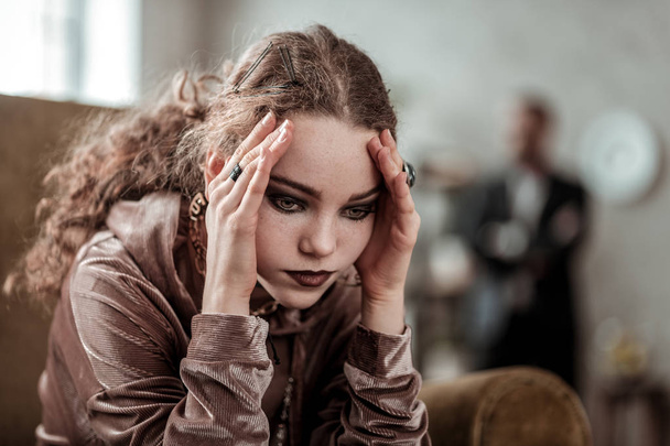 Curly girl wearing rings and having dark makeup feeling stressed - Фото, изображение