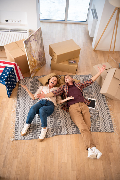 overhead view of happy excited couple laying on floor at new home - Photo, Image