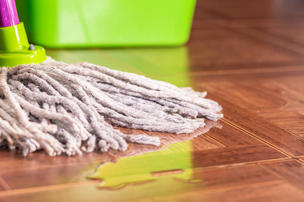 Rope mop on the tile floor and a puddle of water. - Zdjęcie, obraz