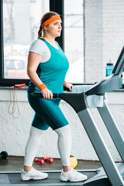 focused overweight girl workouting on treadmill in gym - Фото, зображення
