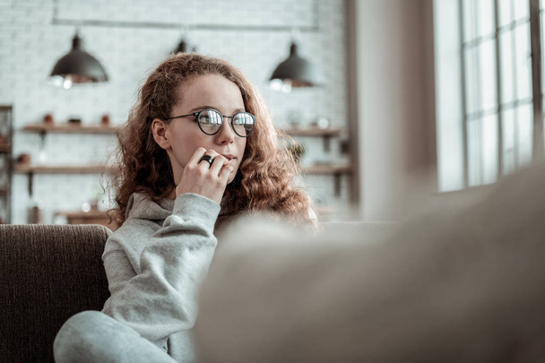 Girl wearing glasses feeling thoughtful talking to therapist - Фото, изображение