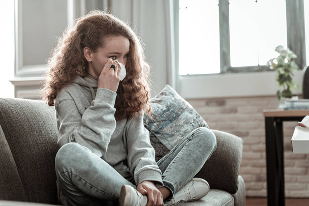 Curly dark-haired teenage girl holding napkin while crying - Fotoğraf, Görsel