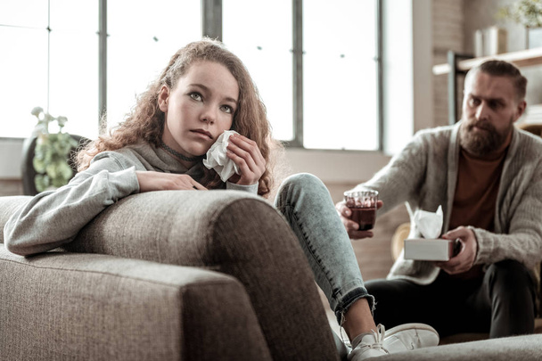 Dark-haired teenager sitting with her back to therapist and crying - Valokuva, kuva