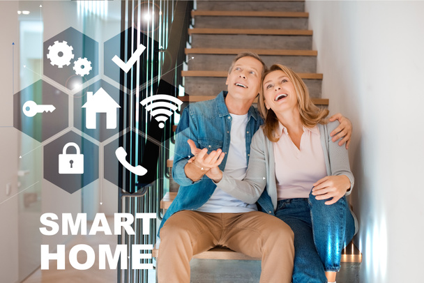 happy husband and wife sitting on stairs at new home, smart home concept - Φωτογραφία, εικόνα