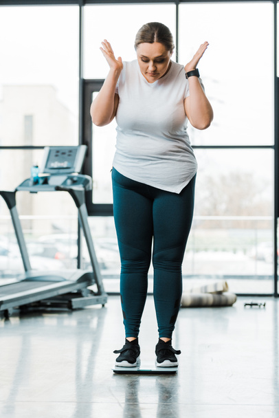 překvapený obézní žena ukázal přitom stát na váhy - Fotografie, Obrázek