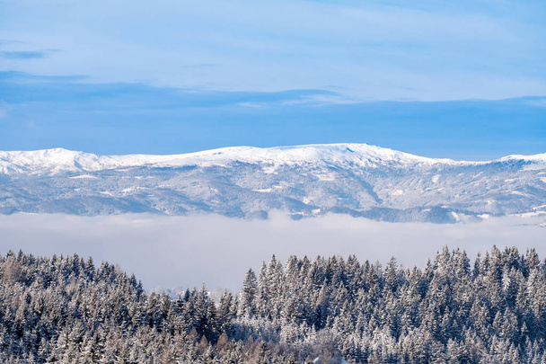Δείτε πέρα από την ομιχλώδη κοιλάδα χιονισμένη οροσειρά Stubalpe, Packalpe - Φωτογραφία, εικόνα