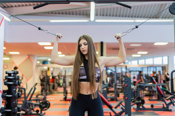 Very beautiful girl trains hands on blocks in the gym. - Photo, Image