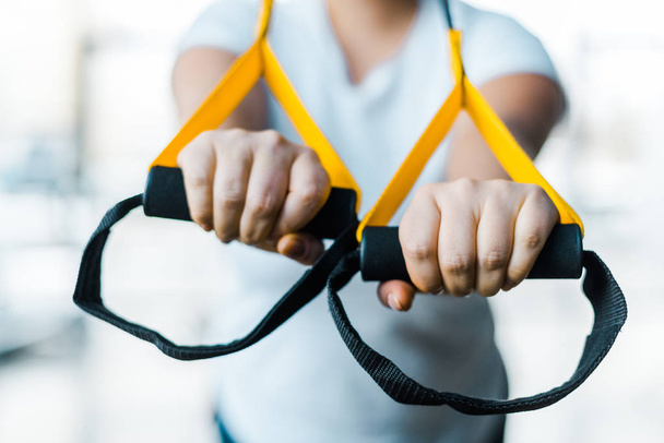 selektiver Fokus der Plus Size Mädchen Trainingsarme mit Aufhängebändern im Fitnessstudio - Foto, Bild
