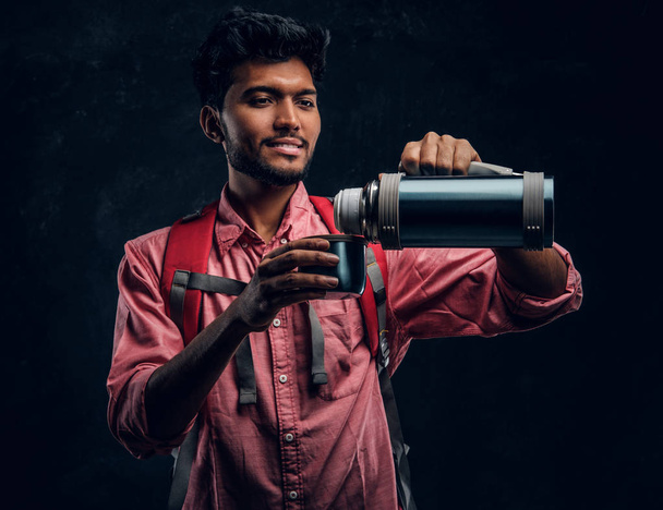Young Indian hiker pours his own tea from a thermos. - Foto, Imagem
